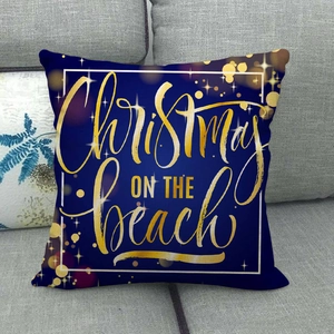Housse de coussin de Noël en lin bleu marine avec imprimé doré sur un canapé gris