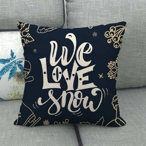 Christmas cushion cover in navy linen featuring We Love Snow lettering and gold snowflake motifs