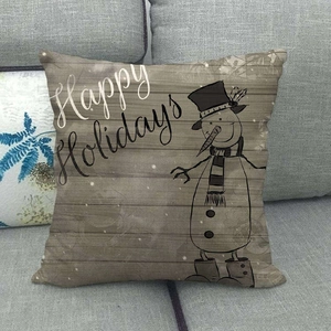 Detail of Christmas snowman linen pillowcase with Happy Holidays text on grey sofa