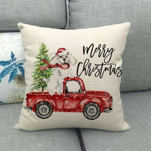 Detail of Christmas linen pillowcase with red truck and dog design on a grey sofa