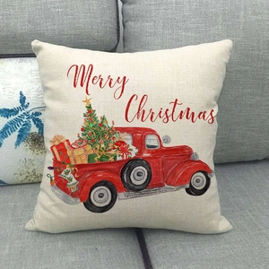 Close-up of linen Christmas pillow case featuring a red truck on a grey fabric sofa