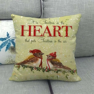 Détail de housse de coussin de Noël en lin avec deux oiseaux sur un canapé gris
