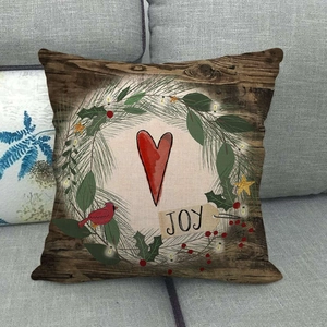 Gros plan sur le texte JOY rustique d'un coussin de Noël en lin avec couronne de sapin