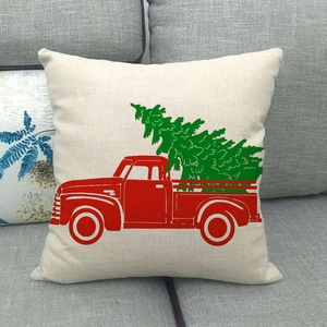 Close-up of linen Christmas pillowcase with vintage red truck and tree on gray sofa