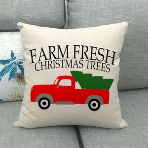 Detail of linen pillowcase with vintage red truck and Christmas tree design on a sofa
