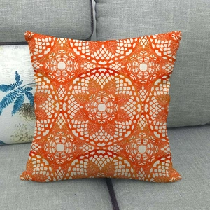 Close-up of geometric orange mandala pattern on linen throw pillow on gray sofa