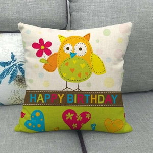 Close-up of linen pillowcase with yellow cartoon owl and Happy Birthday message on a sofa