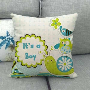 Detail of linen owl cushion cover with It's a Boy text on a grey sofa
