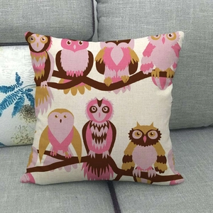 Detail of cartoon owl linen pillow cover showing fabric texture on a grey sofa