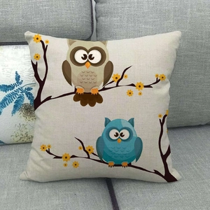 Close-up of linen pillowcase featuring cartoon owl embroidery on a grey fabric sofa