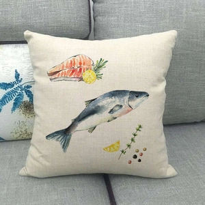 Close-up of linen pillowcase with watercolor fish and lemon print on gray sofa
