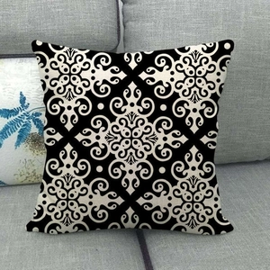 Linen cushion cover with black and white mandala patterns on a grey sofa