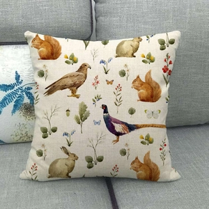 Detailed close-up of a linen pillow cover featuring vintage forest animal and plant prints