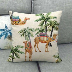 Detail of linen pillowcase with tropical camel and palm tree print on grey sofa