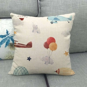 Detail of linen pillowcase with plane and elephant illustration on gray sofa