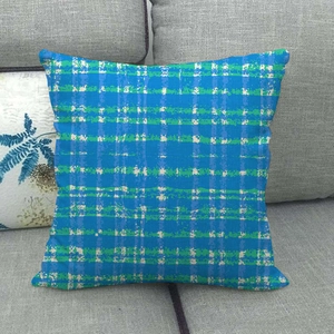 Detail of blue and green geometric plaid linen pillow cover on a grey sofa