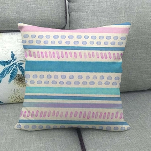 Close-up of geometric linen pillow cover with pink and blue stripes on a grey sofa
