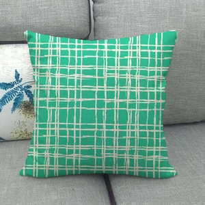 Detail of green and white geometric linen pillowcase with hidden zipper on gray sofa