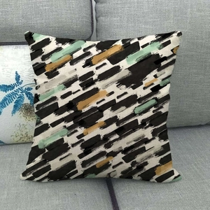 Detail of linen cushion cover featuring geometric abstract brushstroke patterns on sofa