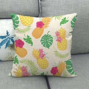 Housse de coussin en lin avec motif d'ananas et feuilles tropicales sur un canapé gris