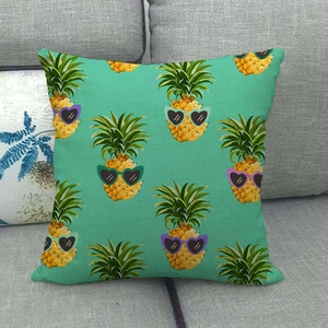 Détail d'une housse de coussin en lin avec motif d'ananas et lunettes de soleil sur sofa