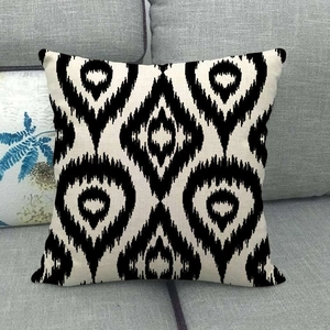 Détail de la housse de coussin en lin avec motifs ikat noirs et blancs sur un canapé gris