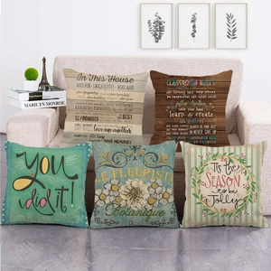 Set of five decorative linen pillow covers with retro floral and quote prints on sofa