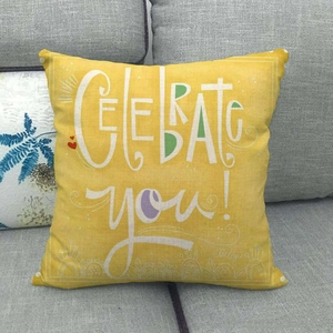 Macro detail of yellow linen cushion with white Celebrate You text on a grey sofa