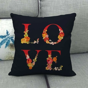 Linen pillowcase with LOVE letters and watercolor floral pattern on a grey sofa