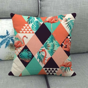 Linen flamingo throw pillow cover with tropical leaf pattern on a grey fabric sofa