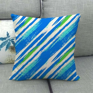 Geometric linen pillow cover with blue and green hand-painted stripes on grey sofa