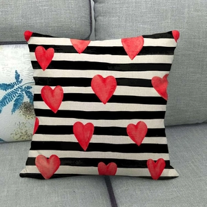 Square linen pillowcase with black white stripes and red hearts on a gray sofa