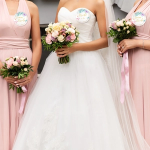 Close-up of Bride to be and Team Bride badges with floral border and gold script