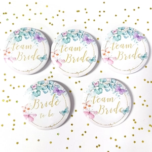 Close-up of Team Bride and Bride to be floral tinplate badges with gold star sequins