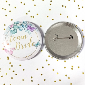 Detailed front and back view of Team Bride tinplate badge with floral butterfly pattern
