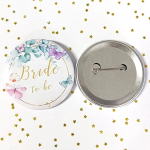 Detailed view of Bride to Be tinplate badge with gold script and floral design