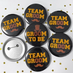 Detail view of Team Groom tinplate badges with safety pin backing for bachelor parties