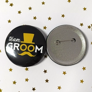 Macro detail of Team Groom tinplate badges with safety pin back and gold star decor