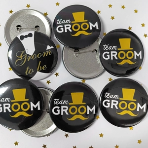 Detail of Groom to be and Team Groom tinplate badges with back pin on white background