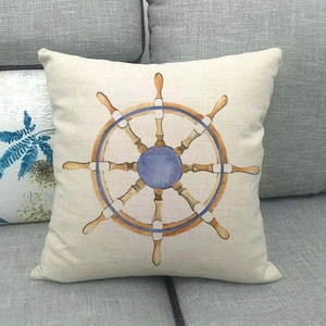 Detailed nautical cushion cover with a ship wheel design on a grey fabric sofa