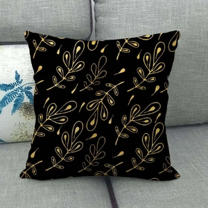 Detail of black linen pillow case with golden leaf pattern on a grey fabric sofa