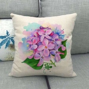 Fodera per cuscino in lino con fiori di lillà acquerello su un divano grigio