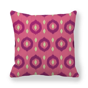Close-up of pink ikat pattern pillow case with purple circles and green leaves