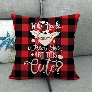 Close-up of buffalo plaid pillowcase with Christmas slogan on a grey sofa