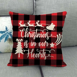 Detail of red and black buffalo plaid Christmas pillow case on a grey sofa