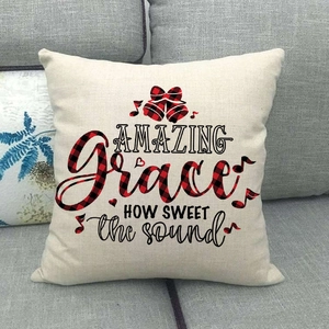Detail of Christmas plaid linen pillowcase with bell print on a gray fabric sofa