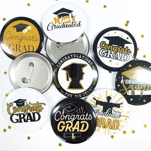 Close-up of graduation badges in black and gold with Congrats Grad slogans and metal pins