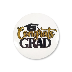 Detail view of round graduation tinplate badge with gold Congrats GRAD text and cap