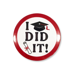 Macro view of the graduation tinplate badge featuring I DID IT text and mortarboard design