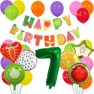 Macro shot of tropical fruit-shaped foil balloons and colorful birthday party set